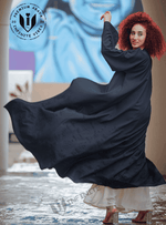 Woman in flowing black designer abaya with curly hair, posing outdoors in Dubai