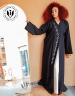 Woman wearing a black designer abaya with floral embroidery, standing by a mirror indoors.