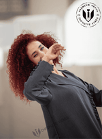 Woman with curly hair wearing modern dark grey abaya with decorative sleeve buttons