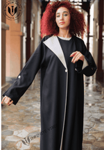 Woman wearing a luxury black and white designer abaya in a covered walkway, UAE fashion
