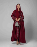 Woman in a maroon luxury abaya with silver embroidery and matching hijab holding a silver bag