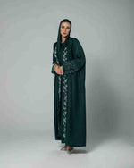 Woman wearing dark green embroidered abaya, modest fashion, UAE style